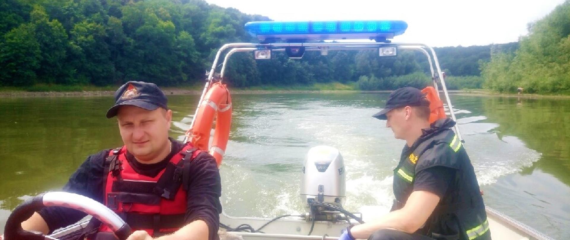 Obraz przedstawia strażaków na łodzi ratowniczej z uratowanym łabędziem