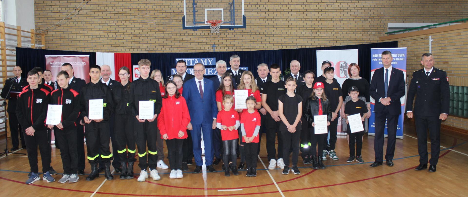 Zdjęcie przedstawia Młodzieżowe Drużyny Pożarnicze z wręczonymi promesami 