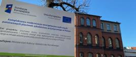 Budynek szkoły z tablicą informującą o termomodernizacji