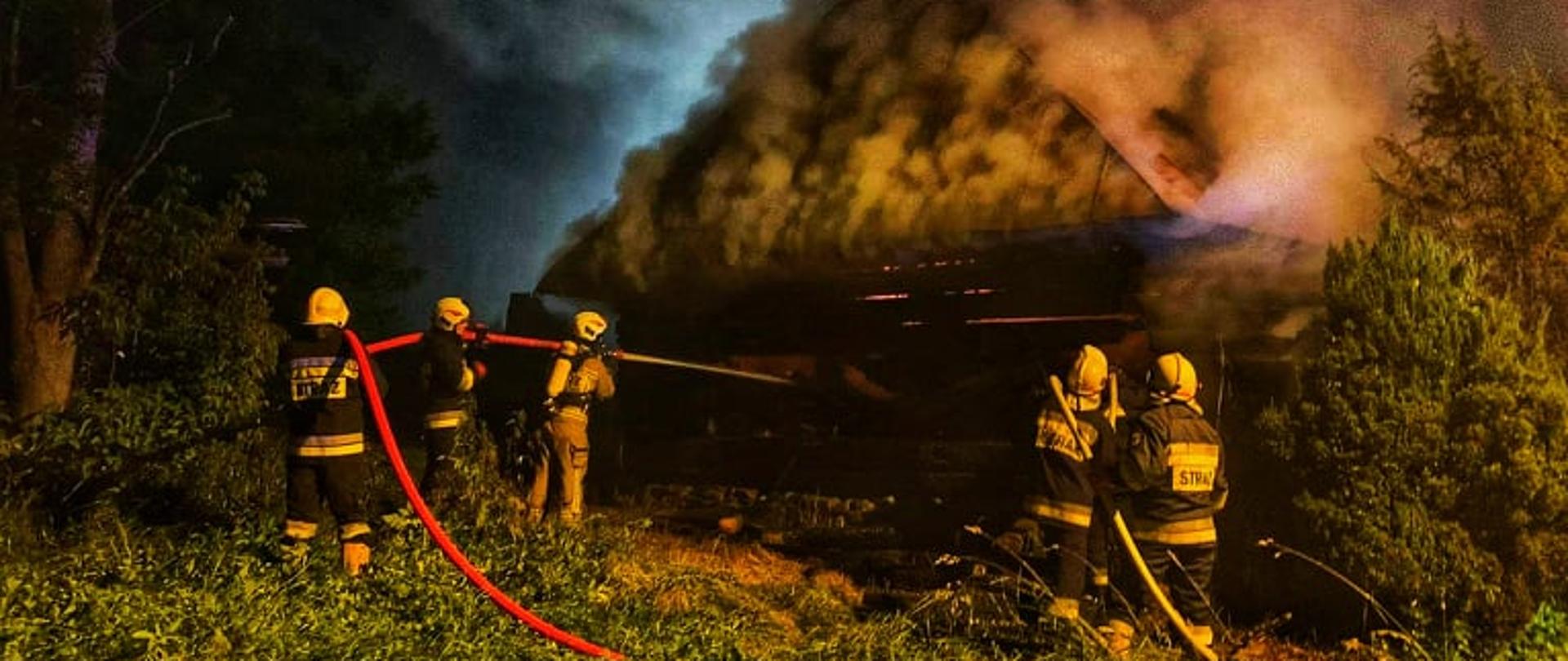 Strażacy gaszą pożar spichlerza. Widać dym wydobywający się z obiektu.