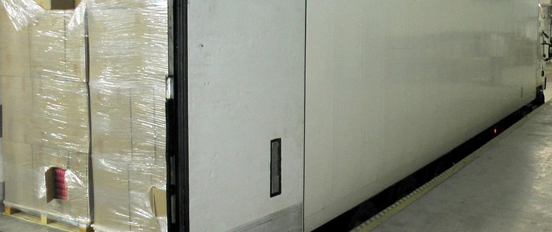 Bok i otwarty tył naczepy samochodu ciężarowego, w środku ładunek nielegalnych papierosów.