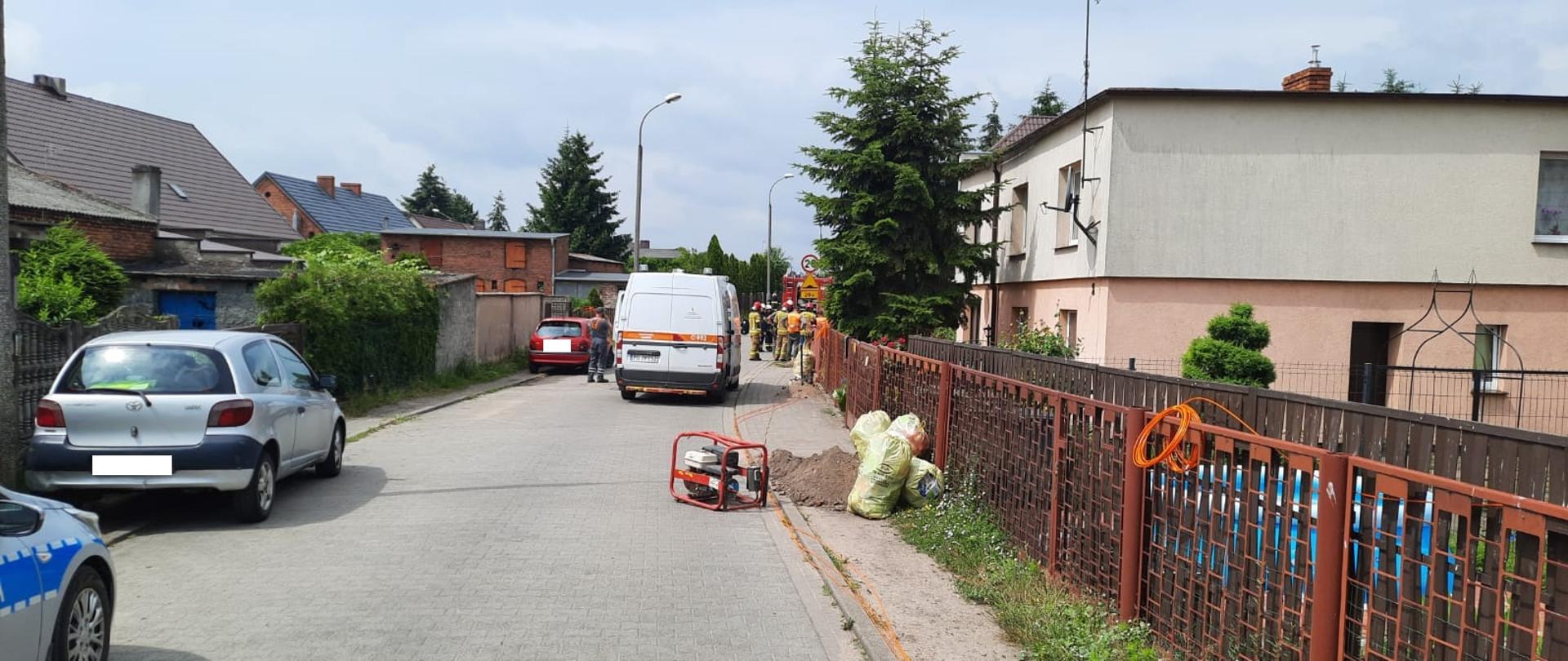 Widać samochód Pogotowia Gazowego, za nim jest kilku strażaków