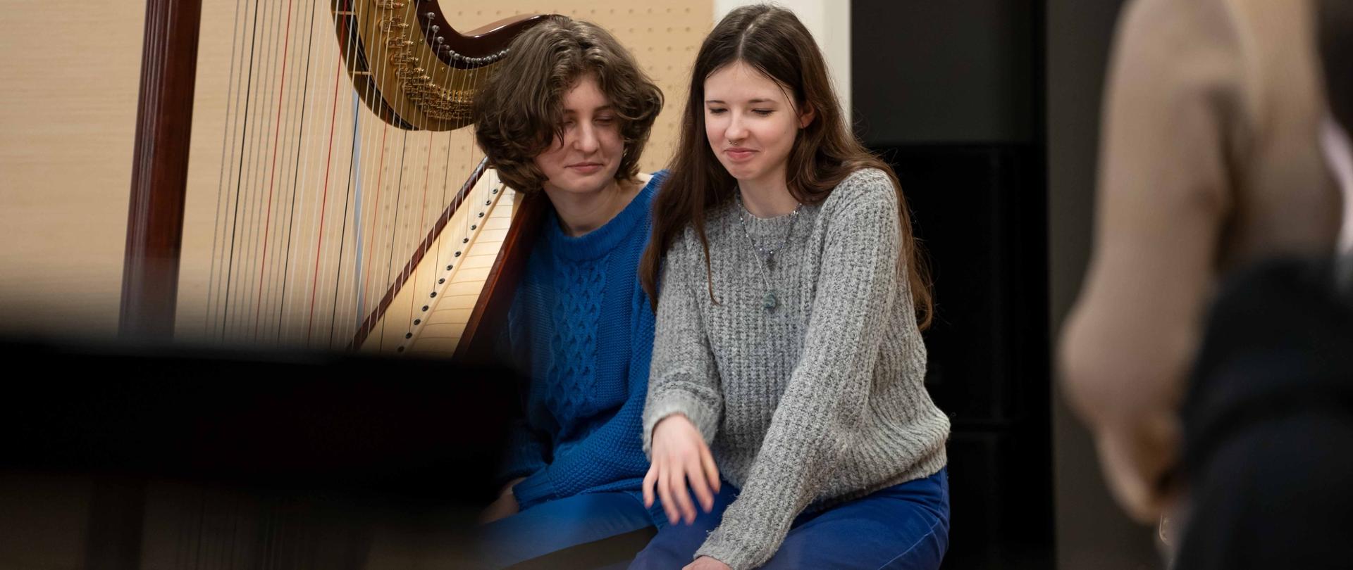 zdjęcie zdjęcie przedstawia dwie uczennice przy harfie na scenie sali koncertowej