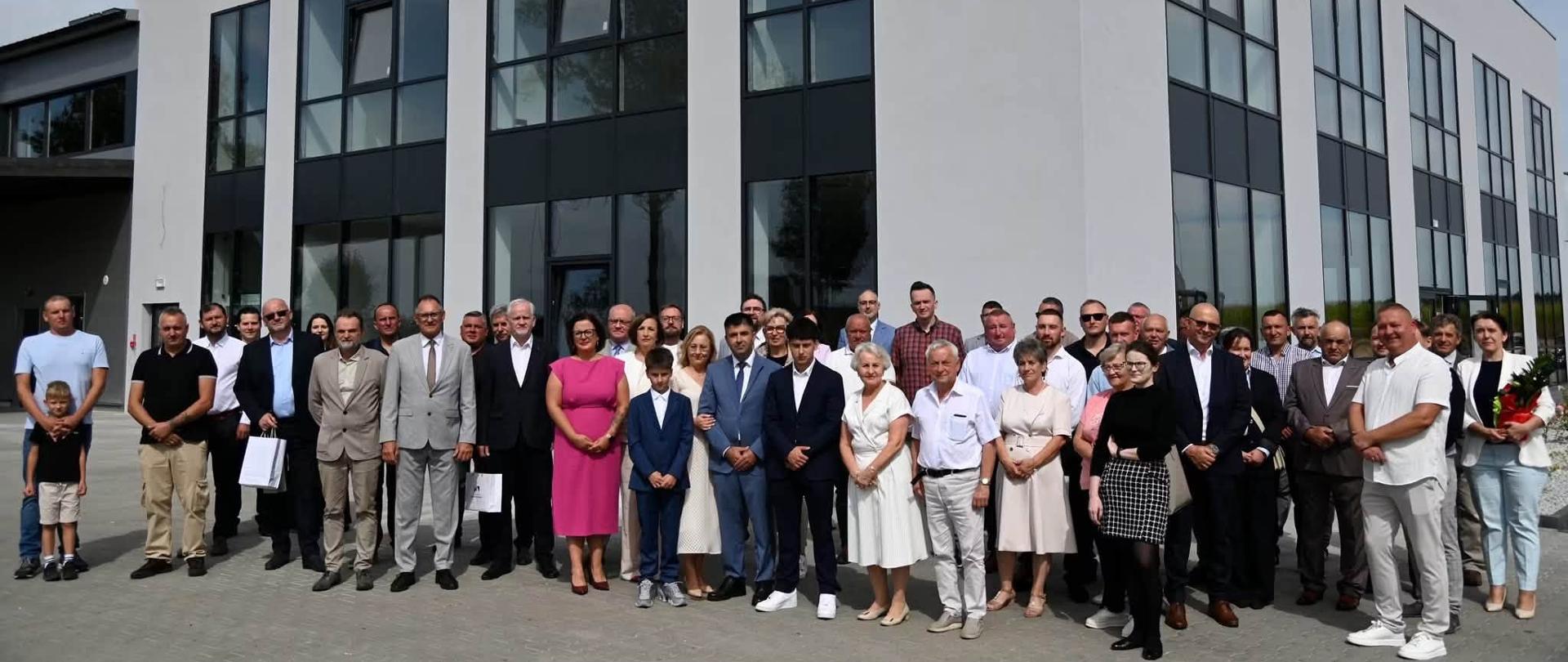 Grupa kilkunastu osób stoi przed budynkiem firmy 