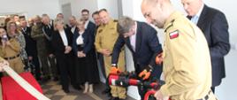 Symboliczne przecięcie węża strażackiego podczas uroczystego otwarcia nowego Stanowiska Kierowania KP PSP w Nidzicy