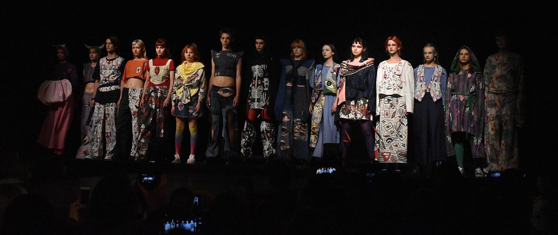 Zdjęcie: na czarnym tle widać stojącą młodzież prezentującą kolorowe stroje