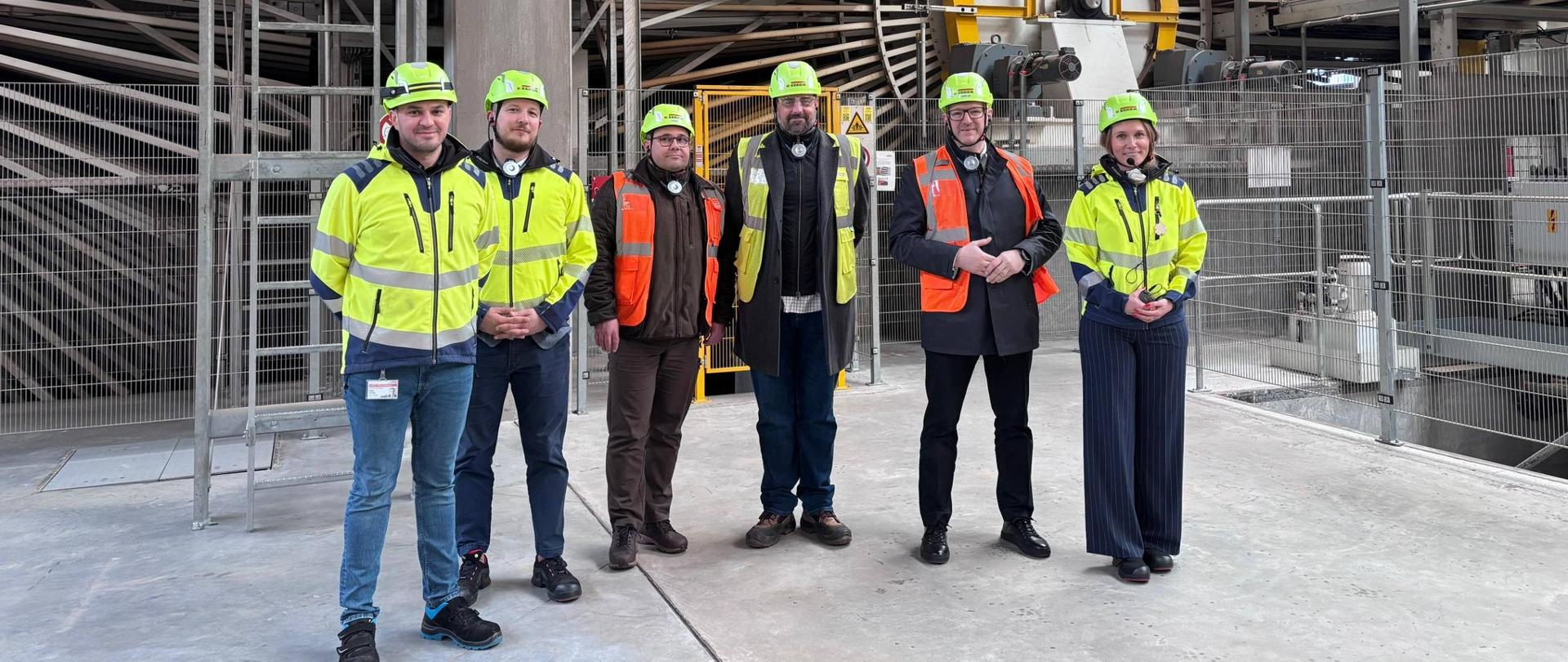 mężczyźni w ubraniach odblaskowych i kaskach pozują do zdjęcia 