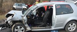 Zderzenie dwóch aut. Okolice Zaborowic. Odcinek jezdni, na którym doszło do wypadku. Na pierwszym planie rozbity volkswagen golf, przy którym stoi strażak, inny w tym czasie sprawdza coś wewnątrz auta. W oddali drugi pojazd. Pomiędzy nimi wóz straży pożarnej. W tle drzewa.