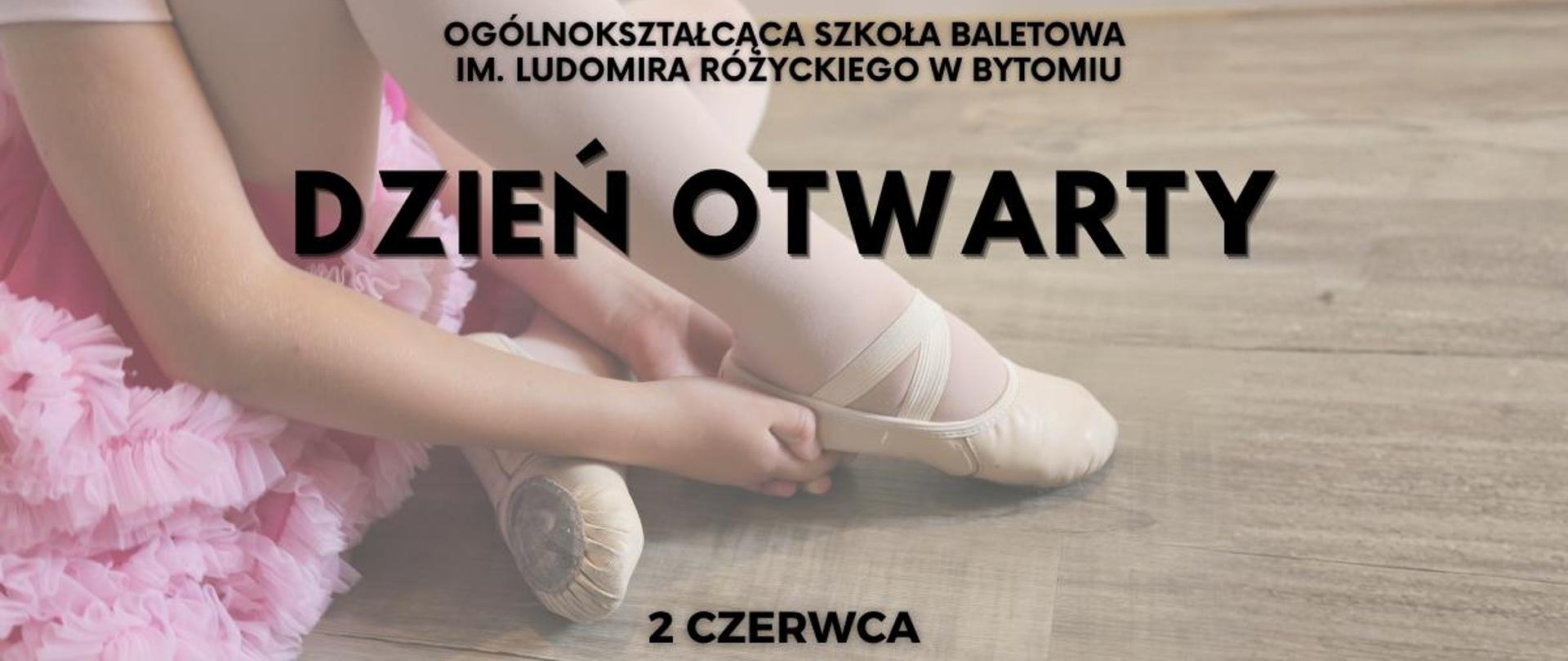 Mała balerina siedzi na drewnianej podłodze w różowym stroju tutu i poprawia baletki przed treningiem tańca klasycznego.