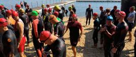 Zdjęcie przedstawia na plaży uczestników Mistrzostw Służb Mundurowych i Paramundurowych w ramach Garmin Triathlon Tour Rawa Mazowiecka 2026 w tle jezioro