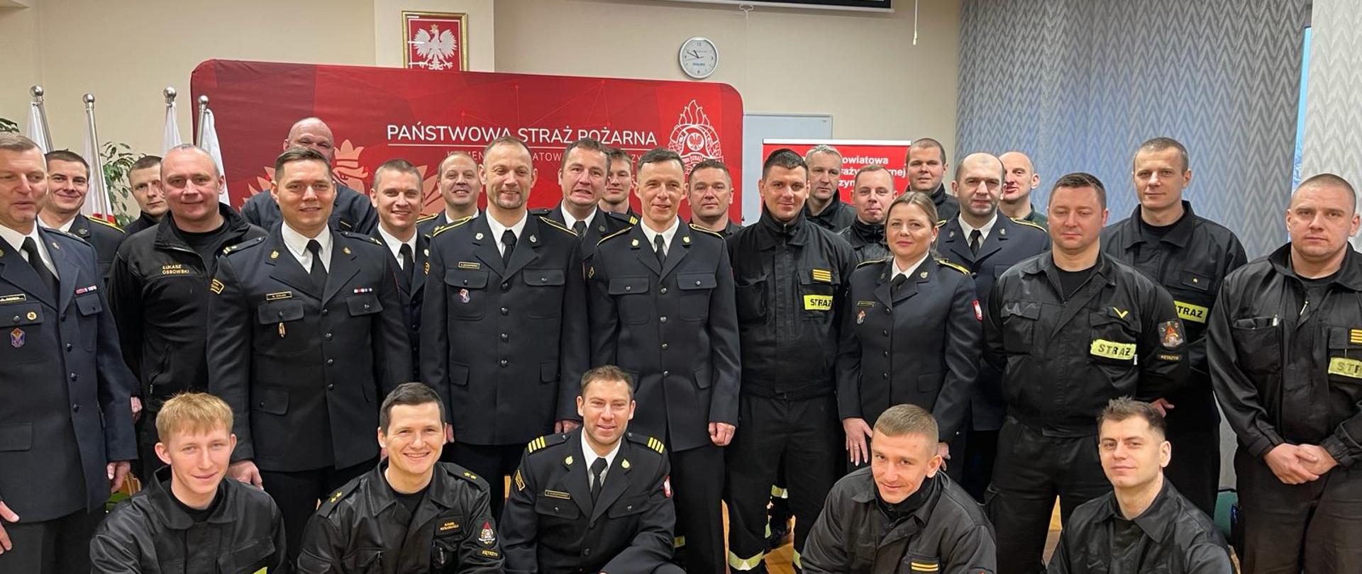 Zdjęcie grupowe na którym znajdują się odchodzący na zaopatrzenie emerytalne asp. Andrzej Szczepański i st. ogn. Przemysław Baran, Komendant Powiatowy i funkcjonariusze kętrzyńskiej Komendy.