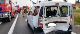 Na zdjęciu na pierwszym planie widoczny jest samochód osobowy marki Dacia Dokker. Pojazd znajduje na pasie jezdni. Na drugim planie widoczne pojazdy straży pożarnej.
