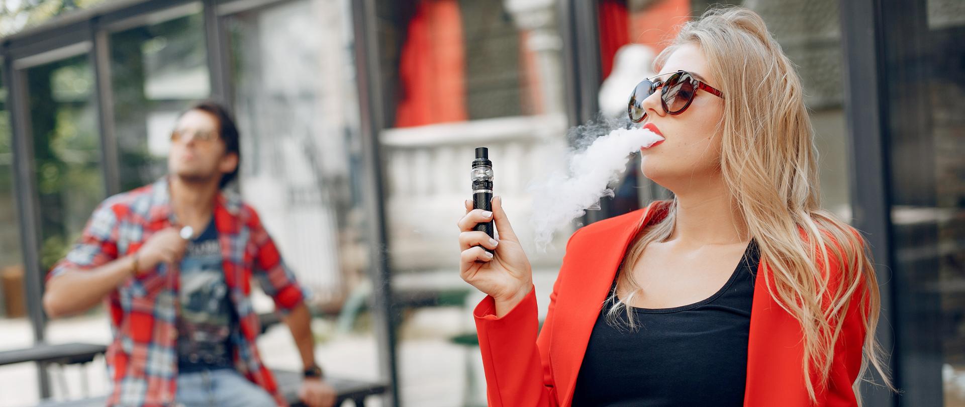 Stylish couple in a city. Two people use the electronic cigarette