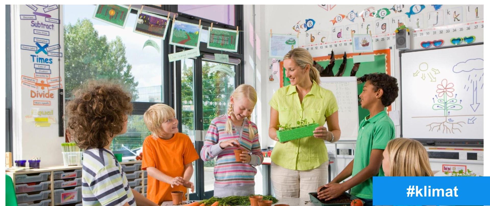 Na grafice znajduje się nauczycielka z uczniami
