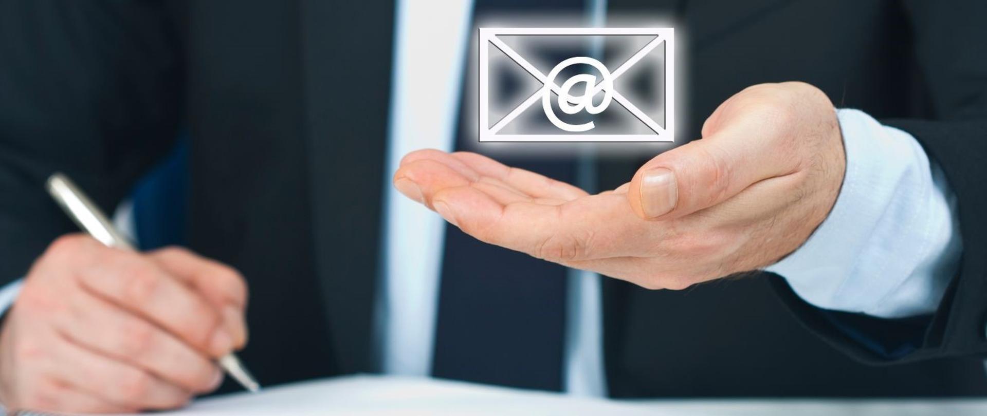 Na grafice widzimy osobę piszącą oraz w 2 dłoni trzyma kopertę ze znakiem maila