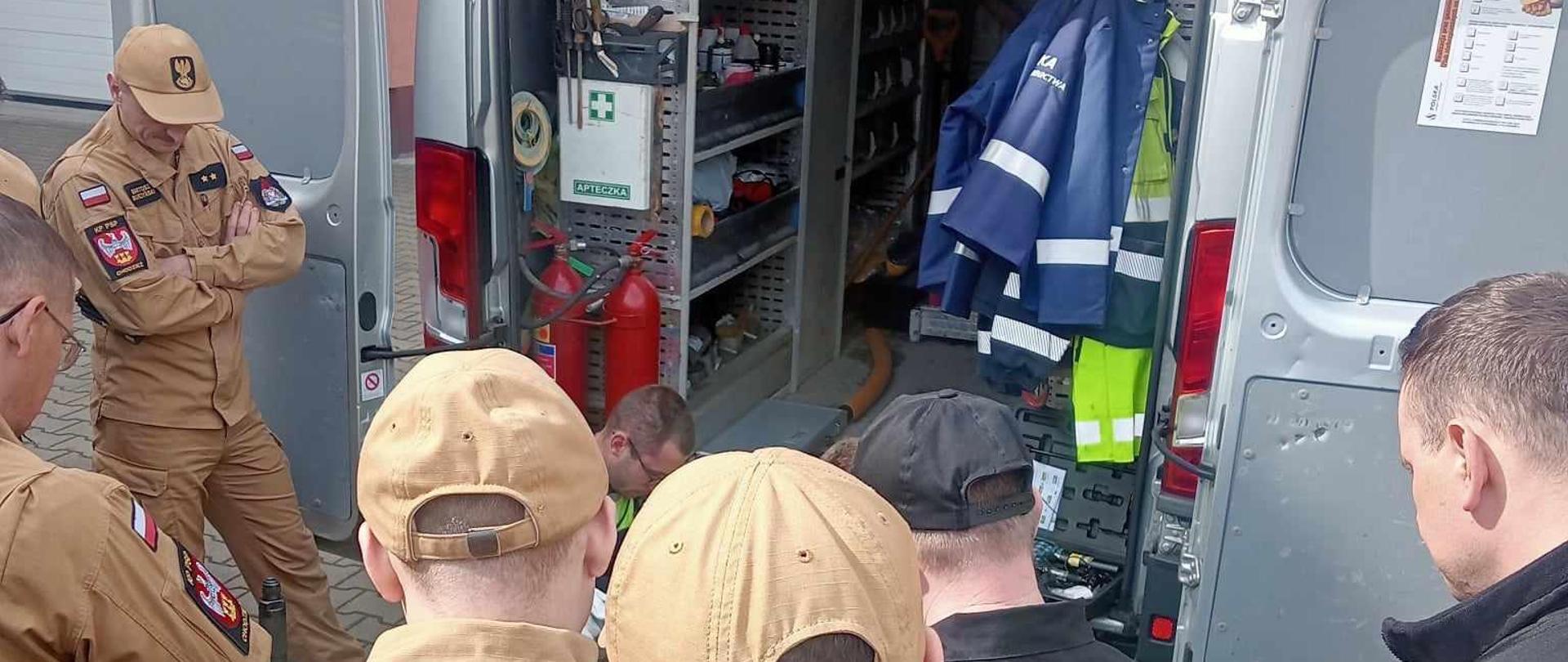 Zdjęcie przedstawia strażaków w trakcie szkolenia z sieci gazowych.
W tle budynek komendy.

