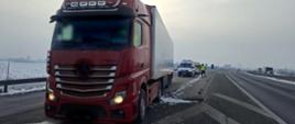 Na pierwszym planie: ciągnik siodłowy z podpiętą naczepą. W tle: za zatrzymanym zestawem ciężarowym stoi oznakowany furgon mazowieckiej Inspekcji Transportu Drogowego.