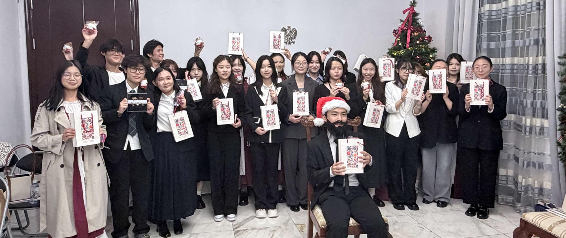Grupa studentów polonistyki GDUFS z konsulem i pracownikami Konsulatu Generalnego RP w Kantonie, trzymających świąteczne upominki, wspólne zdjęcie pamiątkowe.