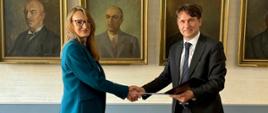 Za stołem stoją Aneta Korczyc, dyrektor ZUOP i dr hab. inż. Maciej Chaczykowski, prof. PW, dziekan Wydziału Inżynierii Środowiska i wymieniają się podpisanymi porozumieniami. 