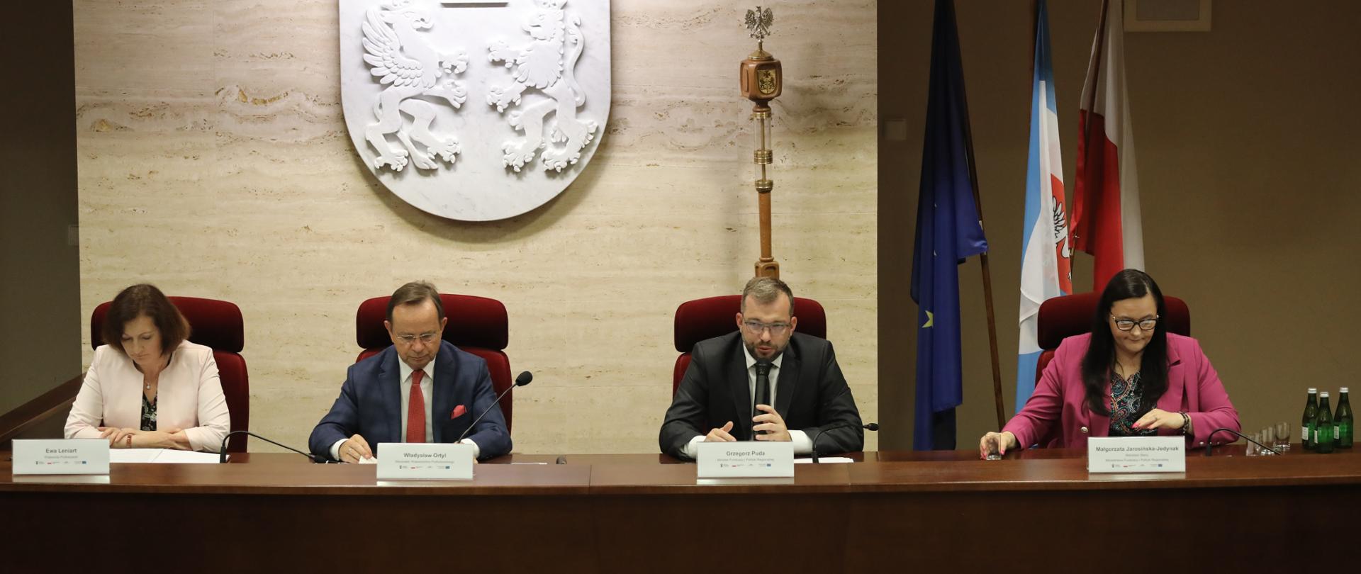 Cztery osoby w sali konferencyjnej siedzą przy stole. Od lewej: wojewoda podkarpacki Ewa Leniart, marszałek województwa podkarpackiego Władysław Ortyl, minister funduszy i polityki regionalnej Grzegorz Puda oraz wiceminister Małgorzata Jarosińska-Jedynak.