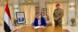 Polish Ambassador Robert Rostek (left) signs the book of condolence. He is accompanied by the defence attaché, Colonel Artur Rochnowski (right)