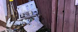 Na zdjęciu widać uszkodzoną skrzynkę elektryczną oraz część ogrodzenia drewnianego na na skraju chodnika. Zdjęcie wykonane w porze nocnej.
