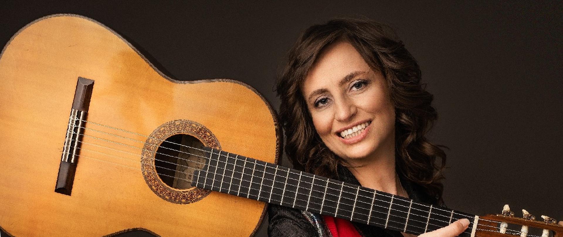 Zdjęcie kobiety trzymającej gitarę. W górnej części napis "PSM I i II stopnia w Zgierzu 21 listopada 2024 warsztaty gitarowe". W dolnej części napis "dr Anna Pietrzak Jak efektywnie ćwiczyć na gitarze".