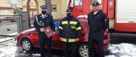 Trzech strażaków na tle samochodu operacyjnego Chevrolett Lacetti