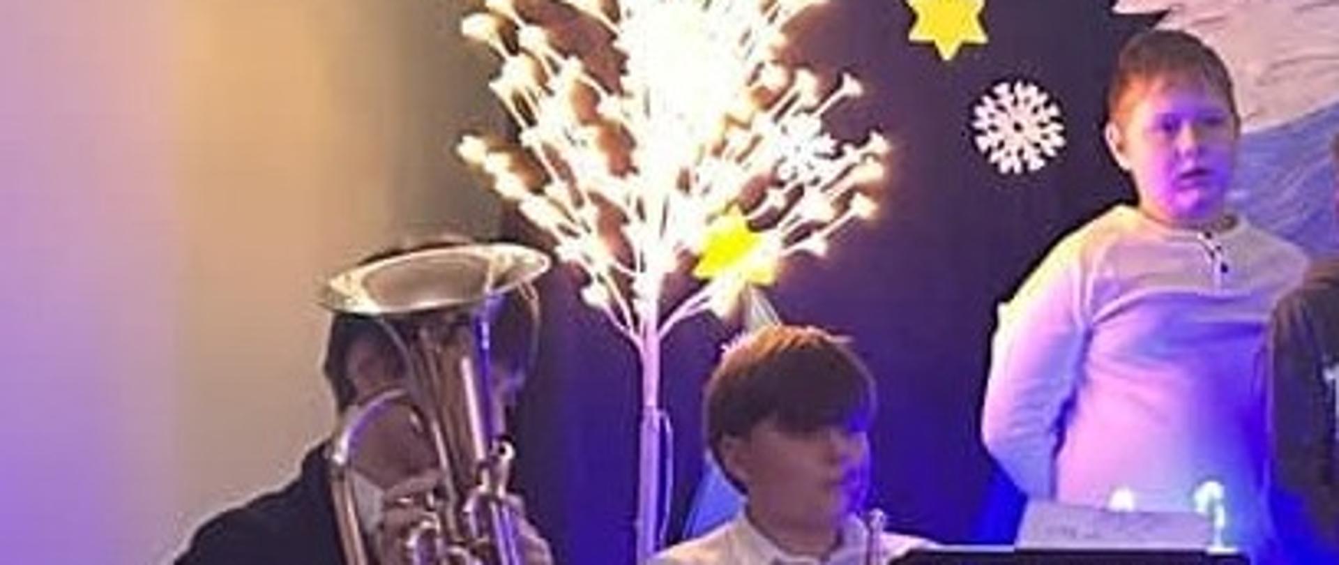 Fotografia przedstawiająca uczniów Państwowej Szkoły muzycznej w Nowym Targu, filia w Jaworkach w scenerii świątecznej grających na instrumentach dętych.