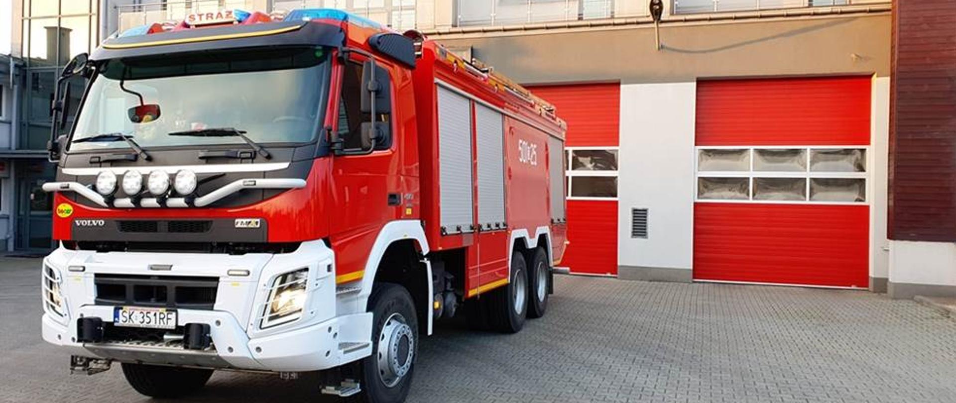 Samochód pożarniczy na tle bram garażowych