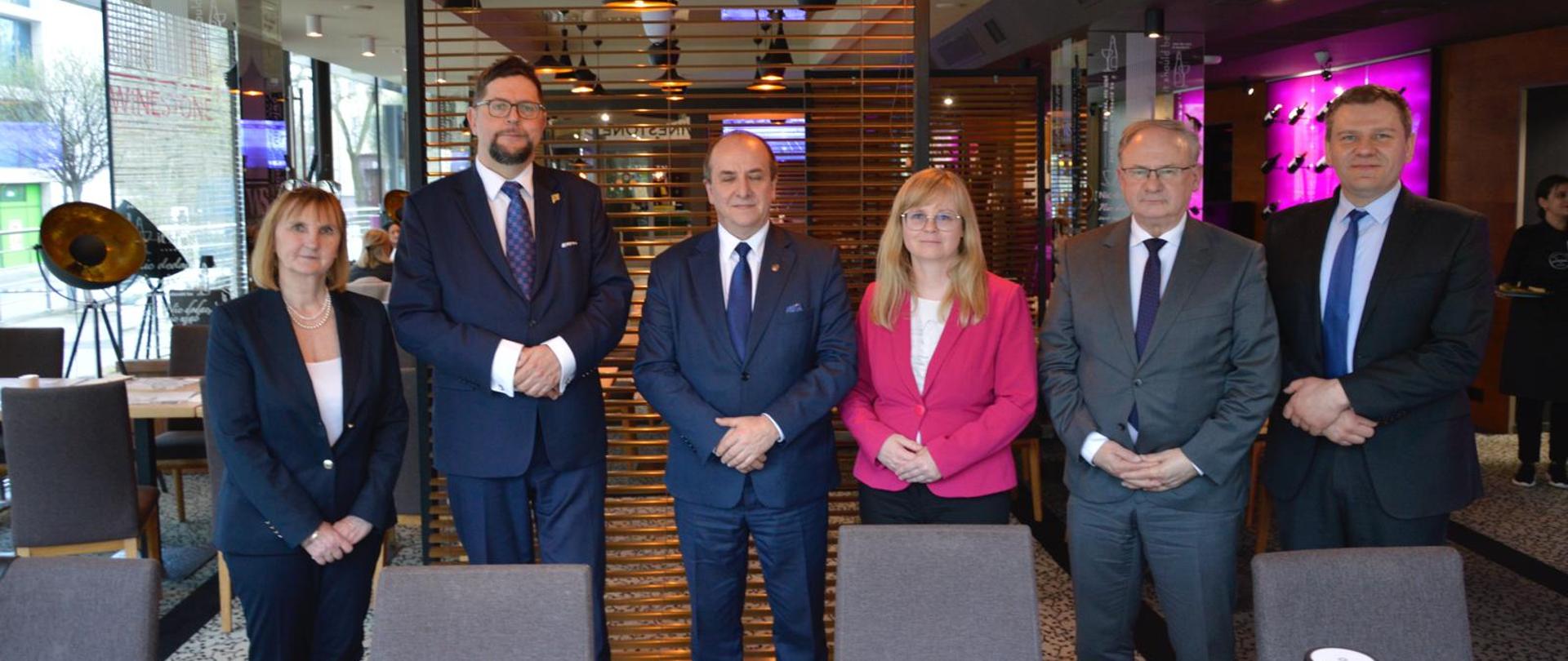 W korytarzu stoi grupa sześciu osób, pośrodku wiceminister Szeptycki.