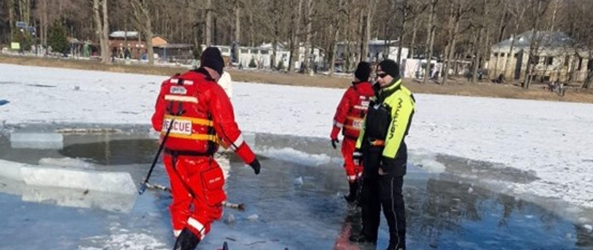 Strażacy stojący na zamarzniętym zbiorniku wodnym