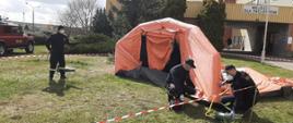 Strażacy rozstawiający namiot pneumatyczny przed szpitalem