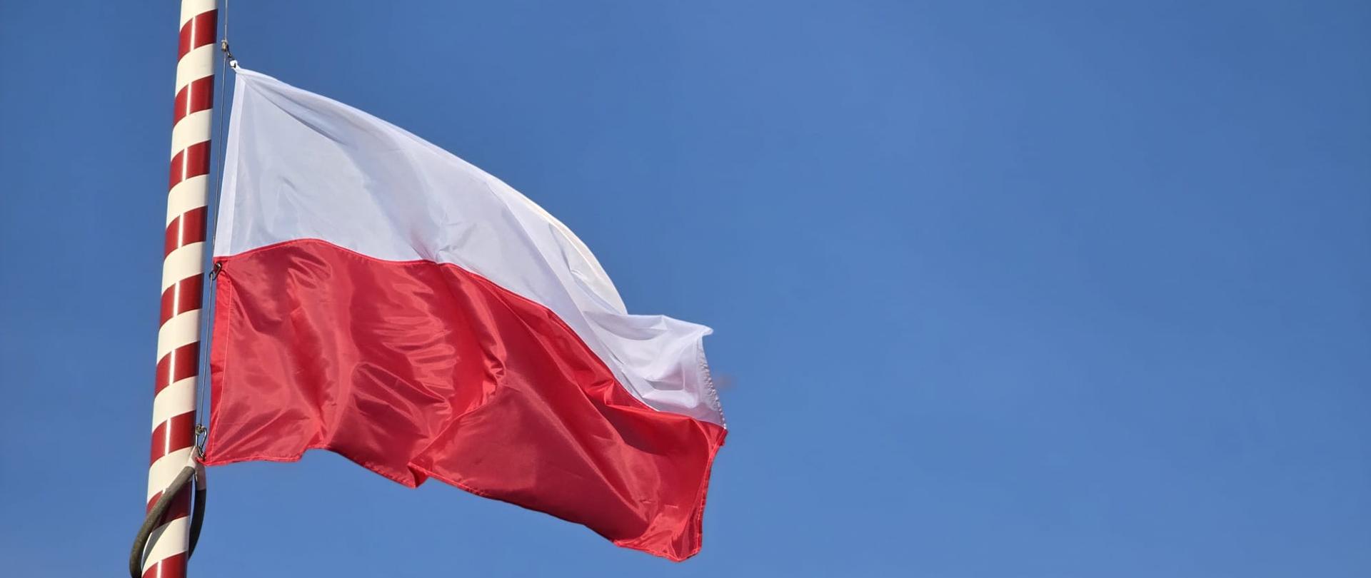 Na zdjęciu flaga Rzeczypospolitej Polskiej na maszcie na tle nieba