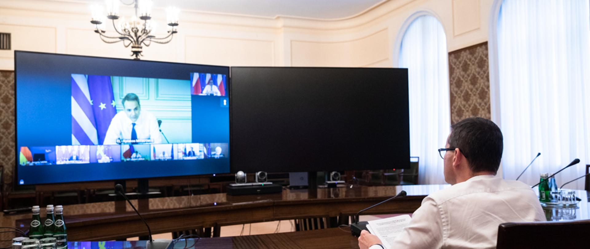 Widok zza pleców premiera Mateusza Morawieckiego na ekran wideokonferencji.