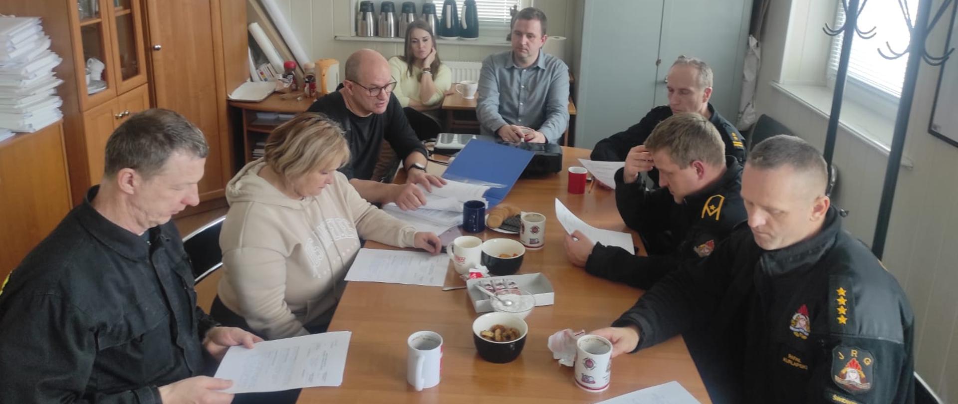 Zdjęcie przedstawia sale na której siedzą przy stole funkcjonariusze i pracownicy cywilni KPPSP Świdwin i słuchają prowadzącego szkolenie.