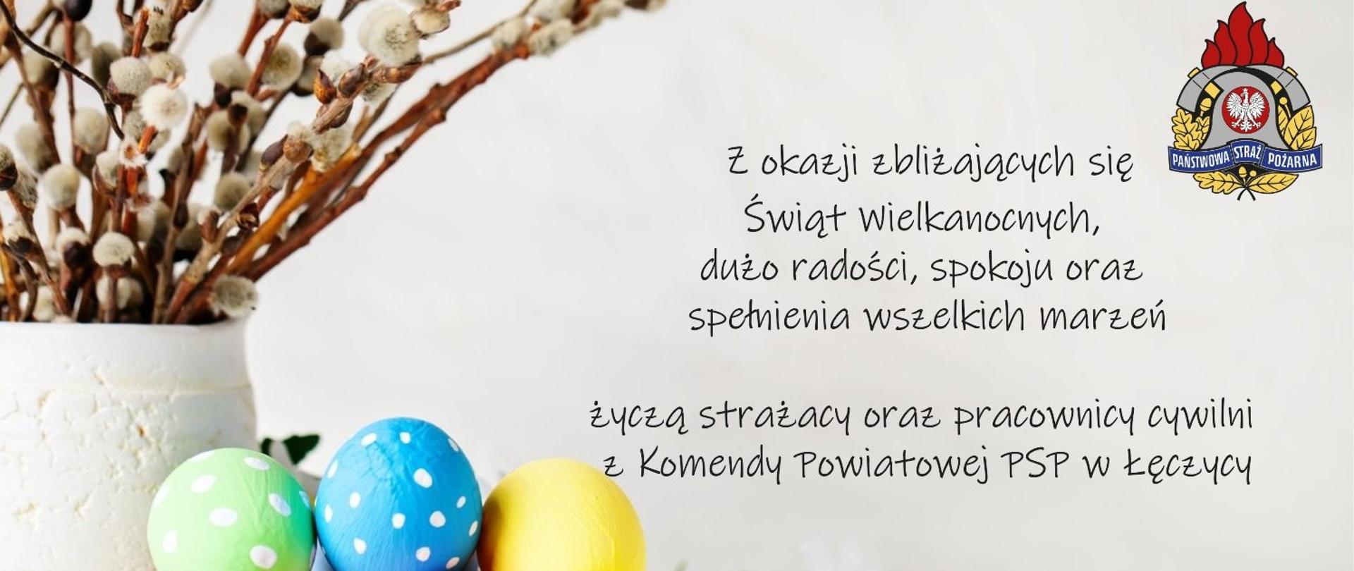 Kartka świąteczna z kolorowymi pisankami w koszyku i gałązkami bazi w tle. Po prawej stronie znajduje się tekst z życzeniami wielkanocnymi od strażaków i pracowników cywilnych Komendy Powiatowej PSP w Łęczycy. W górnym prawym rogu znajduje się logo PSP.