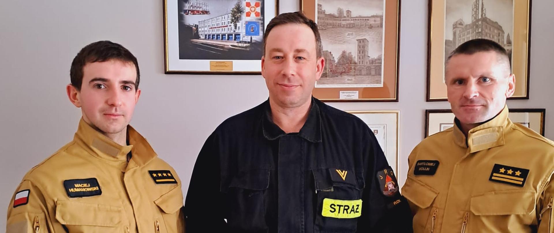 Zdjęcie przedstawia trzech strażaków ubranych w mundury, pośrodku osoba, która otrzymała nagrodę.