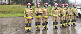umundurowani strażacy stojący w szeregu w maseczkach