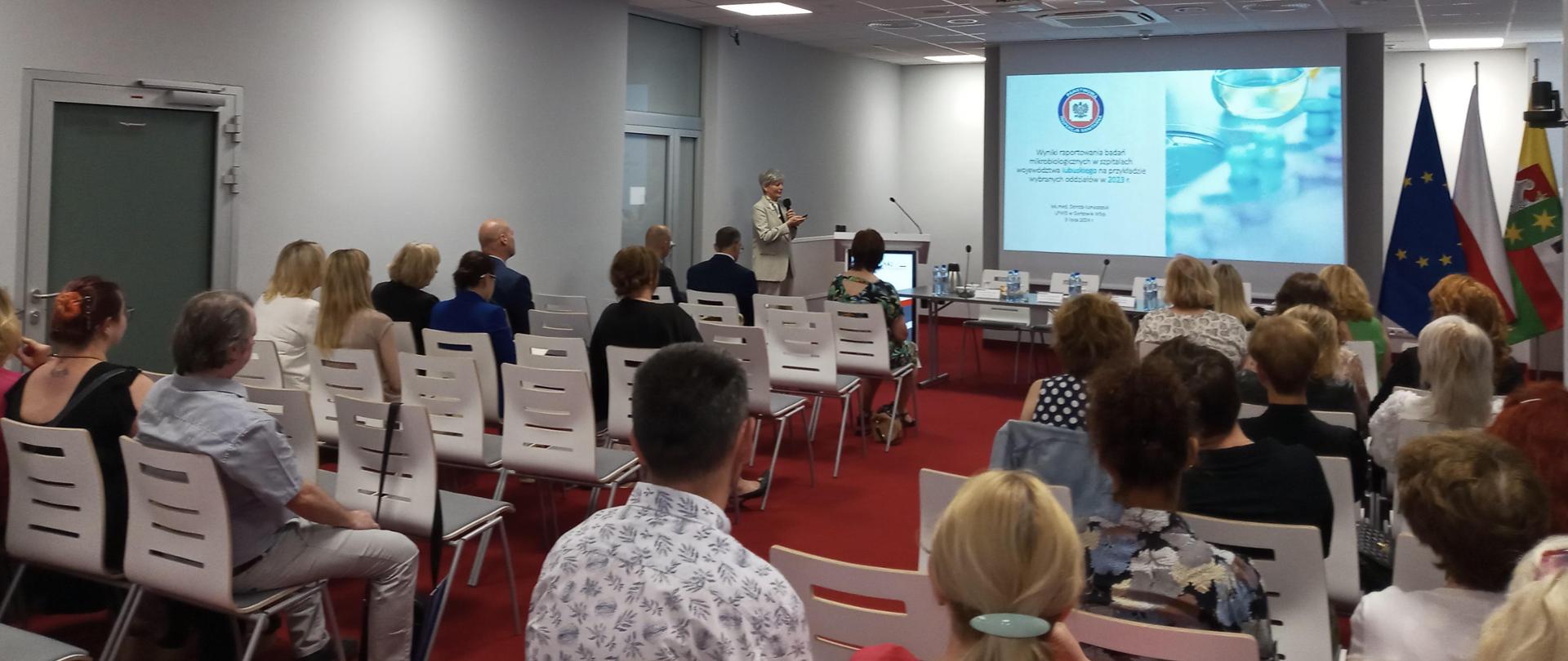 zdjęcie ukazuje spotkanie w sali konferencyjnej LUW na którym prelegent objaśnia slajd z prezentacji na ekranie
