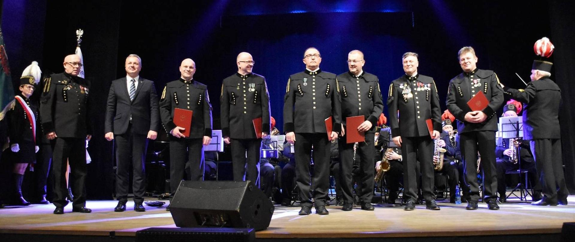 
Górnicy w odświętnych strojach na sali konferencyjnej
