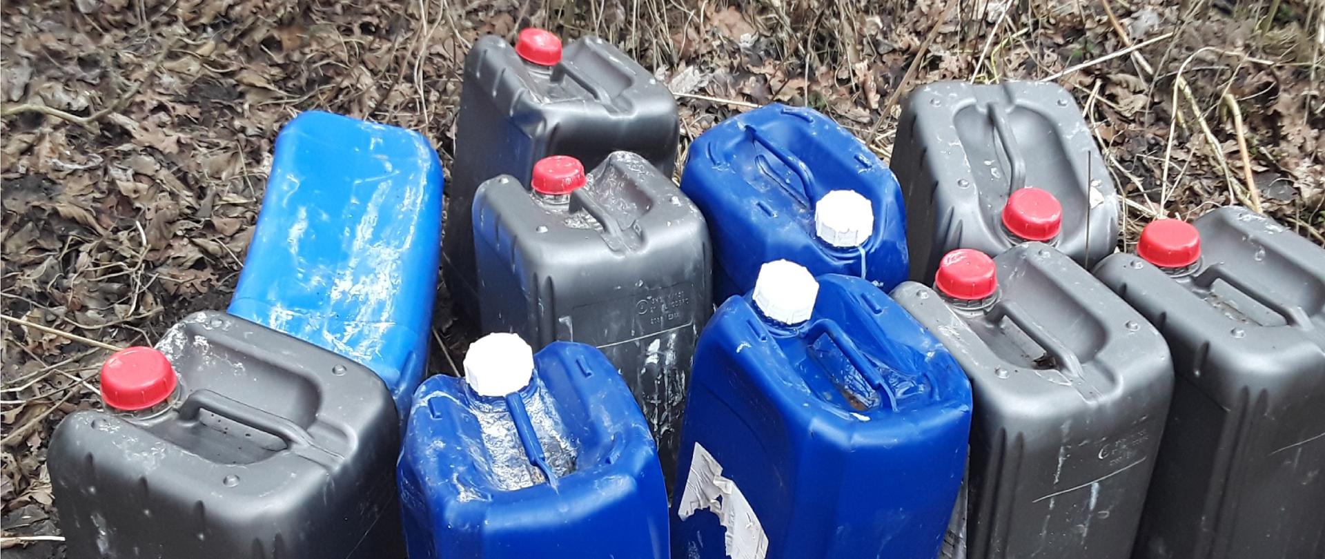 Plastikowe kanistry o pojemności 20 l położone na ziemi w odkrytym terenie.