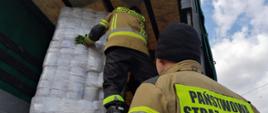 Strażacy KP PSP w Wadowicach ustawiają na skrzyni ładunkowej ciężarówki palety z artykułami higienicznymi. 