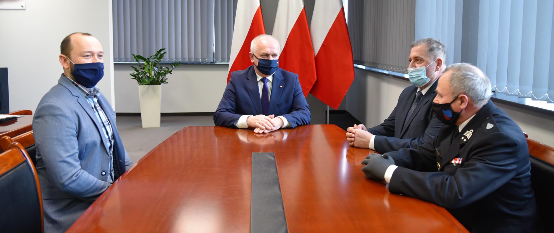 Wojewoda Lubuski rozmawia przy stole z wójtem gminy Niegosławice. W tle flagi.