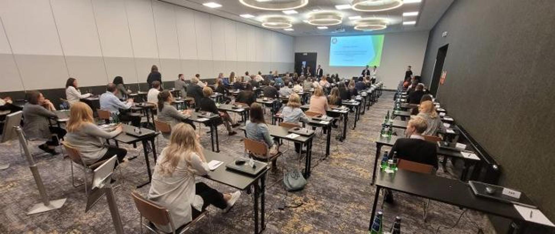 Kilkadziesiąt osób siedzi w sali i czeka na egzamin 