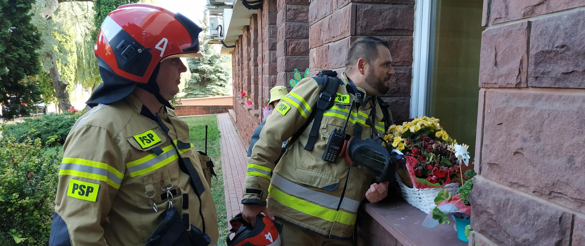 Dwaj strażacy stojący przy oknie 