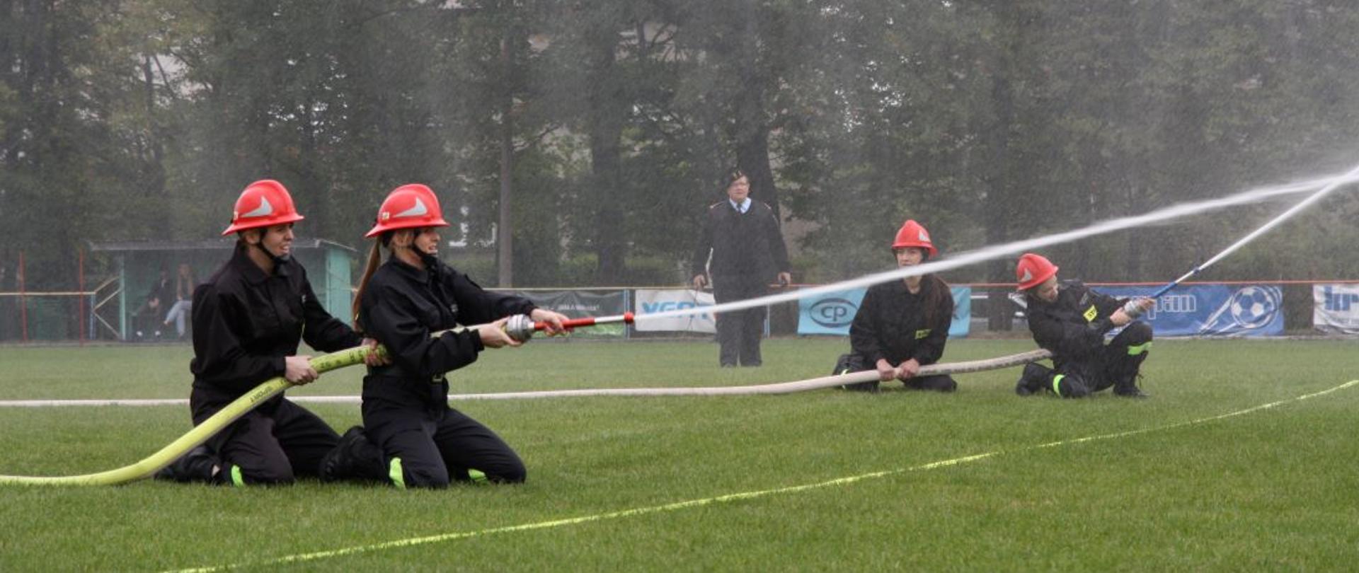 zawody sportowe osp, strażacy w ubraniach specjalnych na stadionie 