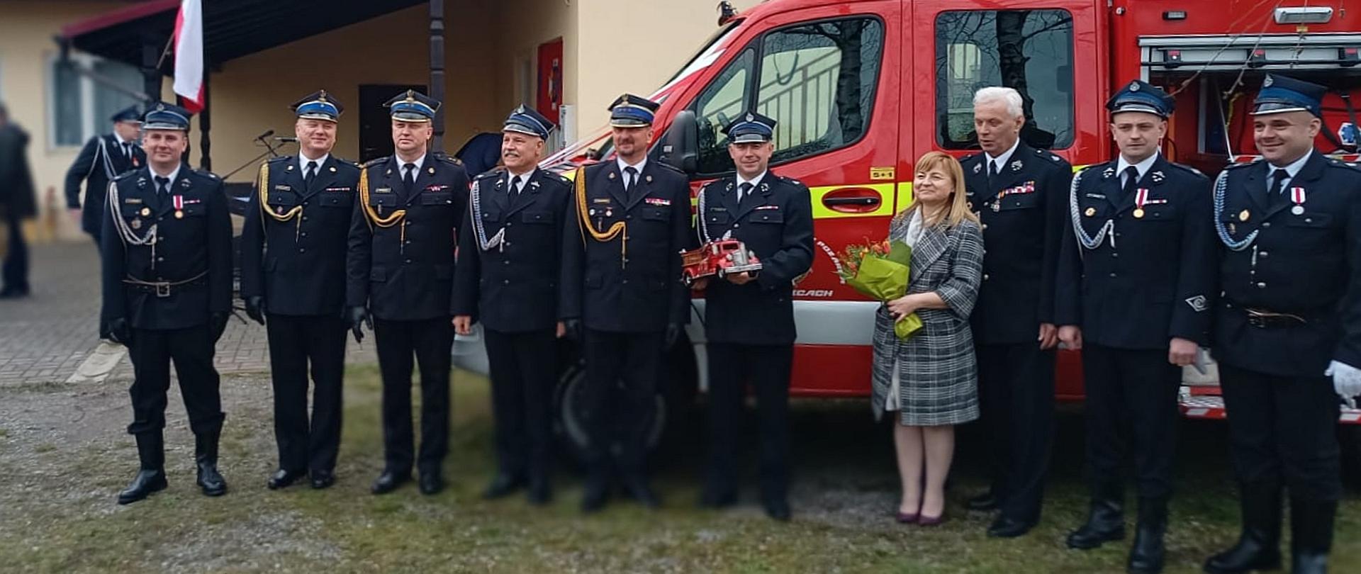 strażacy PSP druhowie OSP oraz politycy pozują na tle samochodu ratowniczo-gaśniczego