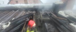 Uszkodzony dach pomieszczenia kotłowni, widać strażaka
