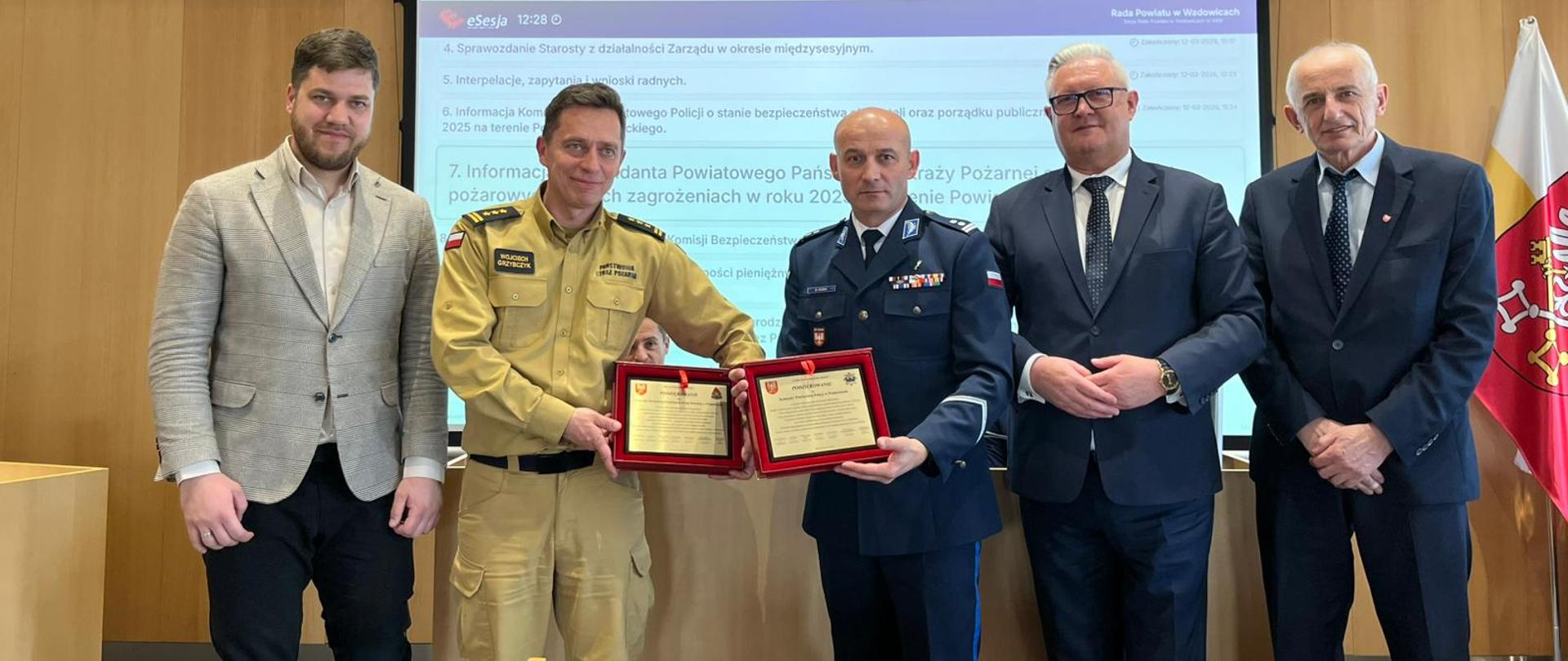 na pierwszym planie zastępca komendanta powiatowego PSP w Wadowicach st. bryg. Wojciech Grzybczyk obok niego komendant powiatowy Policji w Wadowicach mł. insp. Mateusz Dańda obok niego starosta wadowicki Mirosła Sordyl, a obok niego przewodniczący Rady Powiatu w Wadowicach Józef Łasak na sali sesyjnej starostwa powiatowego w Wadowicach